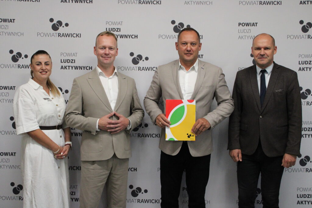 powierzenie obowiązków Dyrektora. 4 osoby a tle baneru z Logo Powiatu rawickiego.